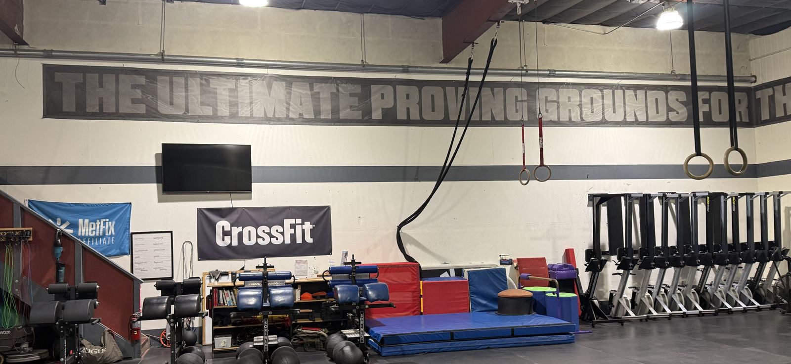 The banner along the gym wall: The Ultimate Proving Grounds for the Fittest on Earth