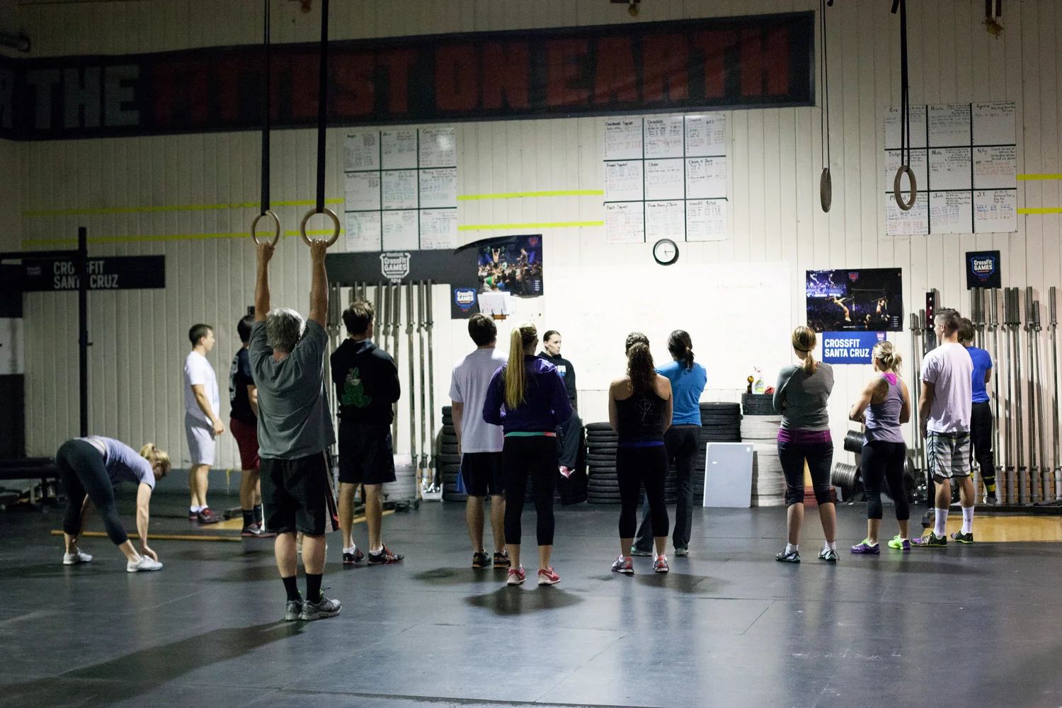 A class hanging from the rig together under the sign that reads Fittest on Earth